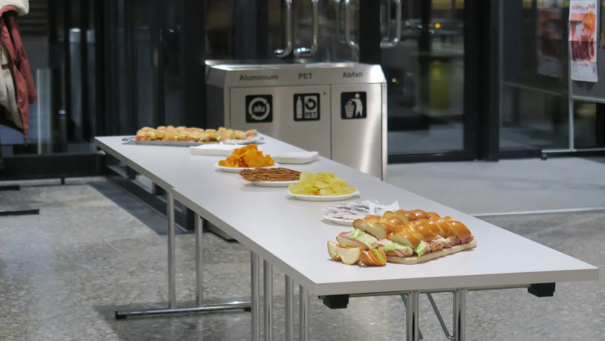 Auf dem Bild ist ein Tisch zu sehen, auf dem Sandwiches und Knabbereien liegen.